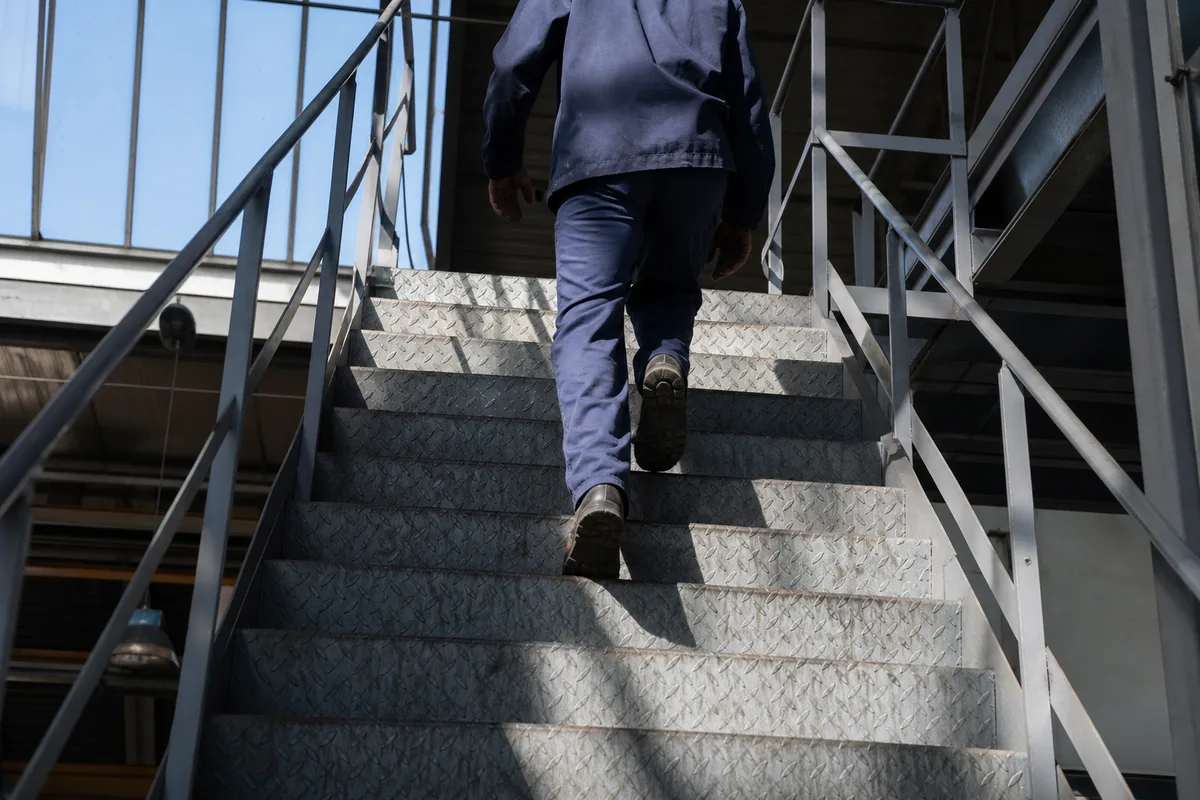 Escalier métallique industriel à marches striées dans un atelier français éclairé par une verrière