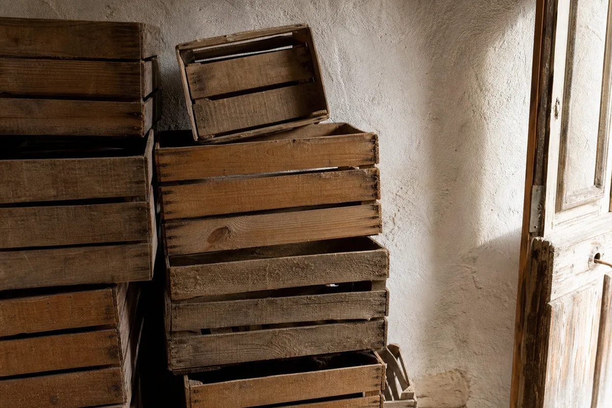 Réserve d&rsquo;une petite entreprise française, cagettes en bois empilées contre un mur chaulé