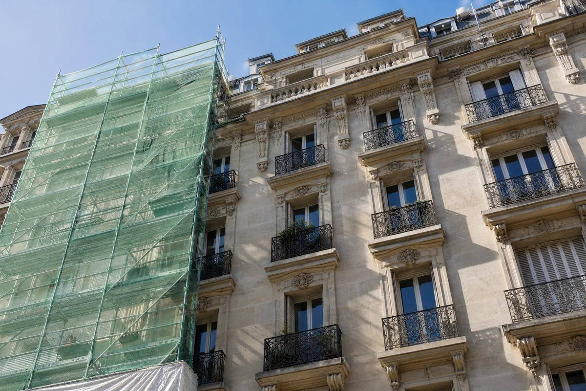 Façade de pierre en cours de ravalement avec échafaudage, ciel clair au-dessus d&rsquo;un immeuble ancien
