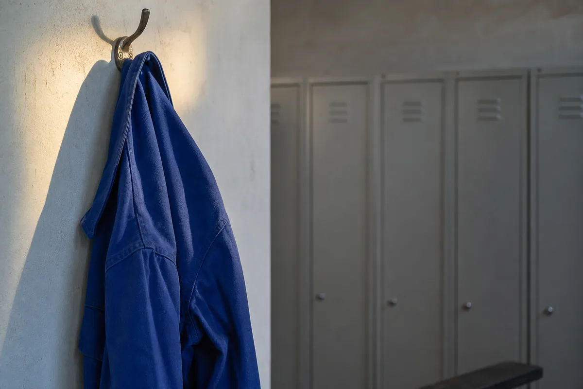 Veste de travail bleue suspendue à une patère dans un vestiaire d&rsquo;atelier